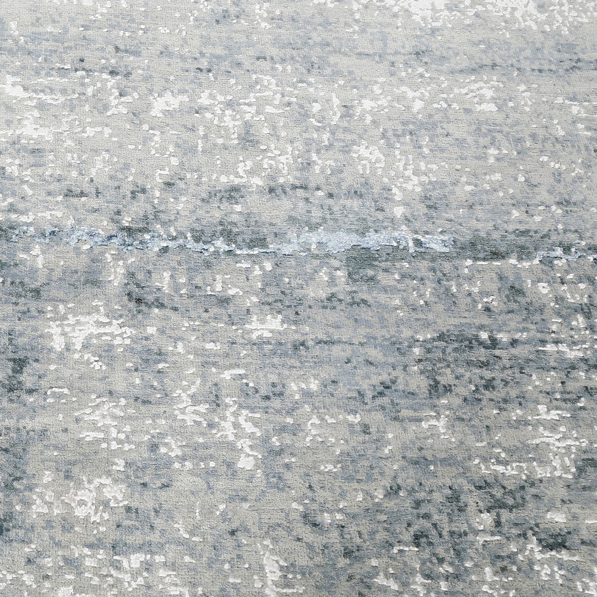 Close-up of the hand knotted wool and viscose texture with silver grey ivory and icy blue abstract detailing