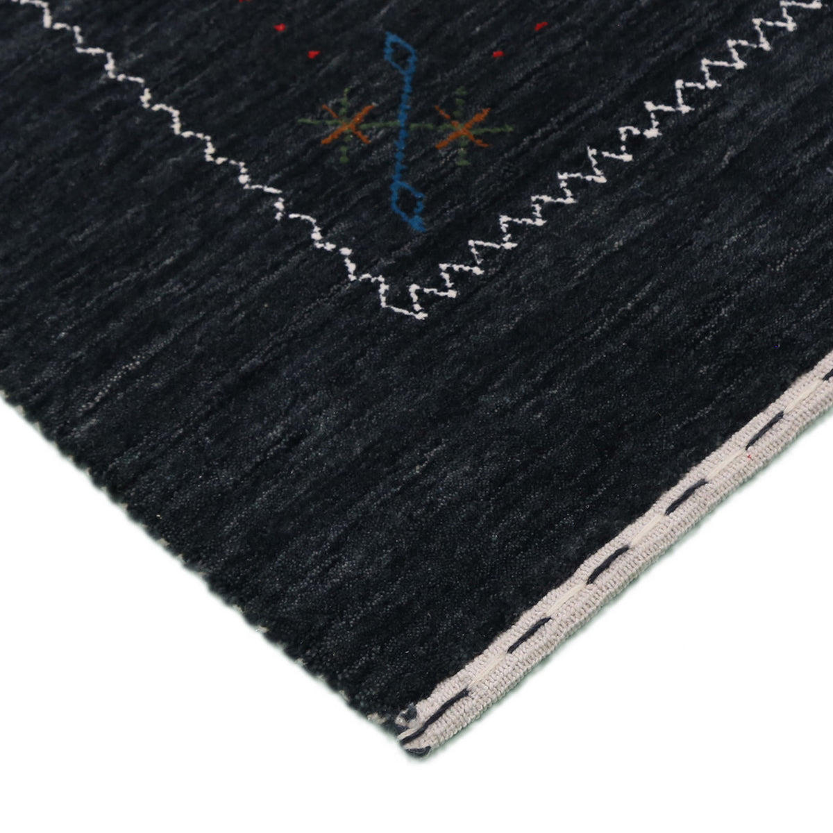 Corner and edge detail of black Hand Woven Loom Lori wool rug showing zigzag geometric border and handcrafted finishing