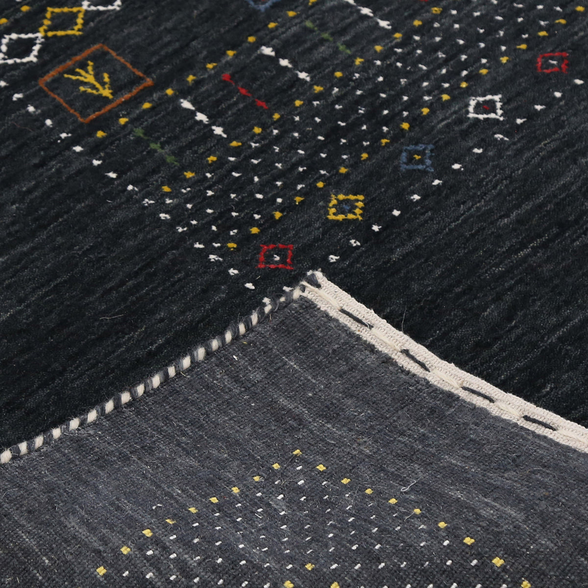 Corner and edge detail of black Hand Woven Loom Lori wool rug showing geometric border and handcrafted finishing