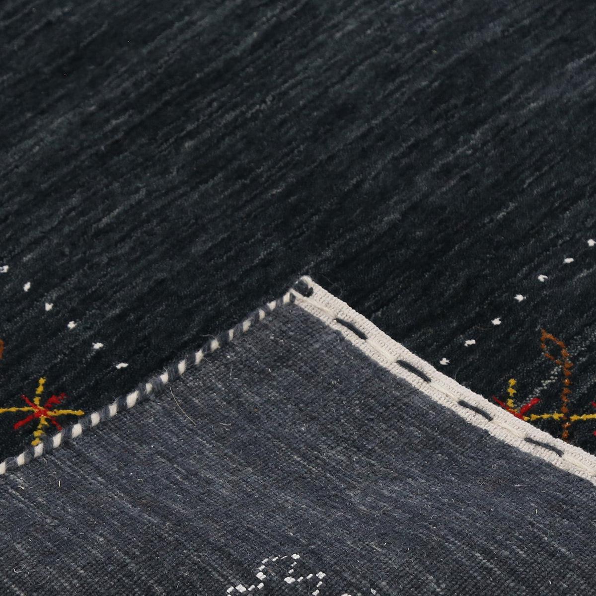 Corner and edge detail of black Hand Woven Loom Lori wool rug showing zigzag geometric border and handcrafted finishing