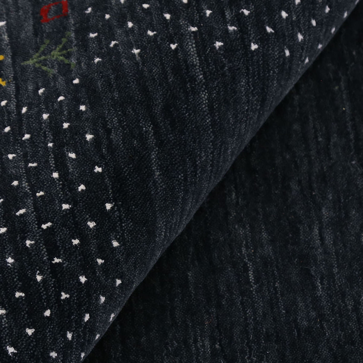 Close-up of charcoal black Hand Woven Loom Lori wool rug showing natural wool texture, botanical symbols and earthy tribal motifs