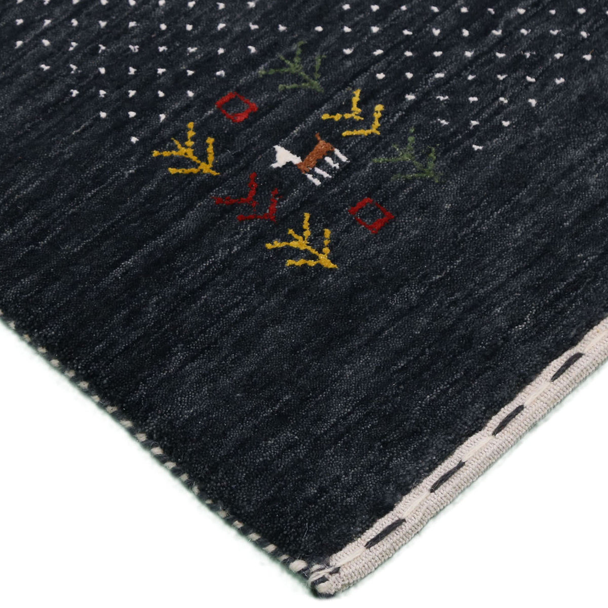 Corner and edge detail of charcoal black Loom Lori wool rug showing ivory dotted sections, folk motifs and handcrafted finishing