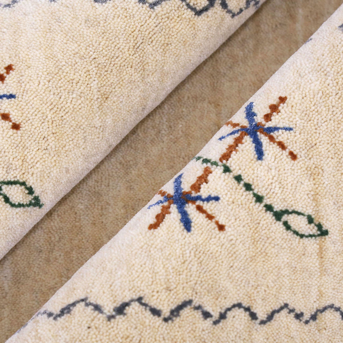 Close-up texture of cream Hand Woven Loom Lori wool rug showing natural wool fibres and delicate floral motif detailing