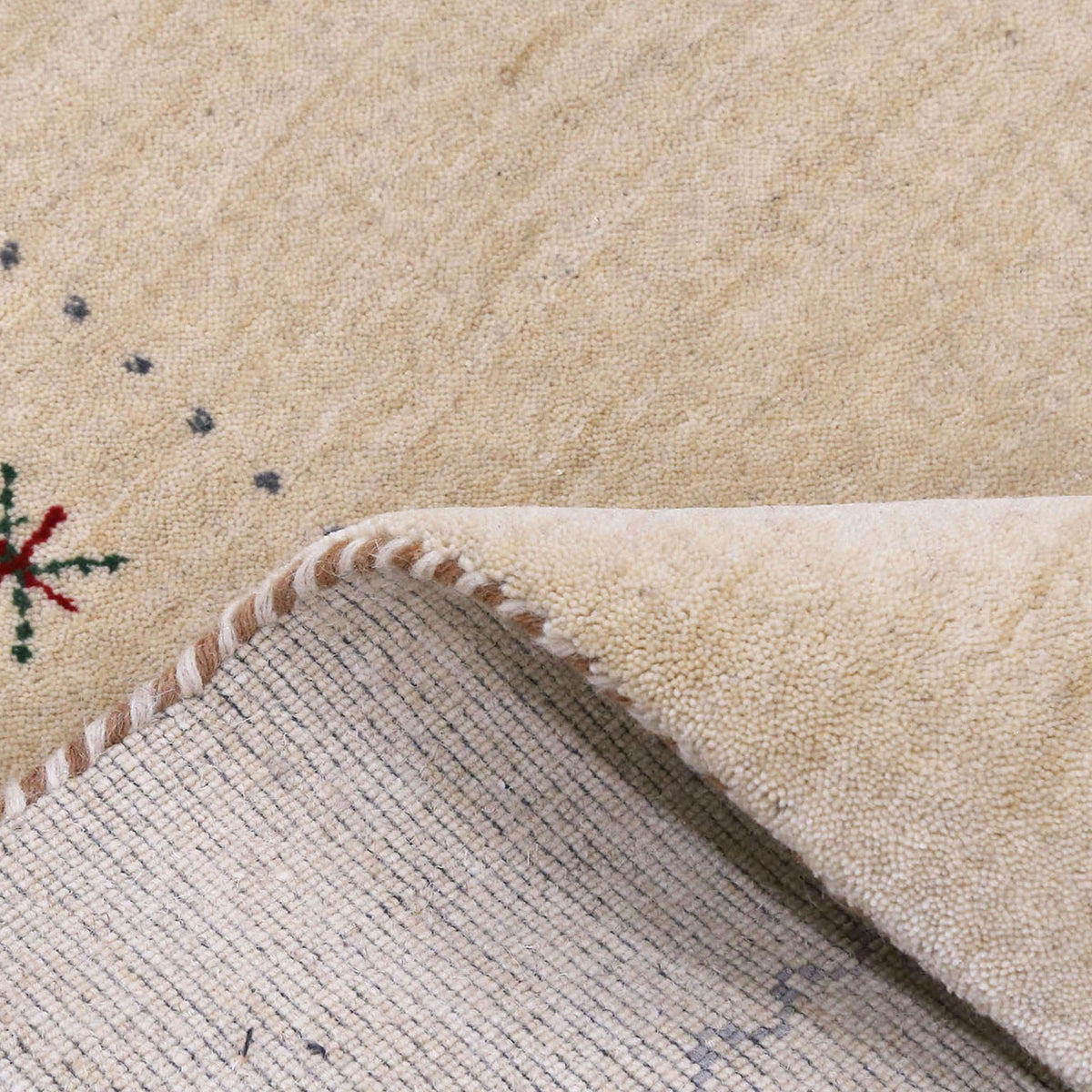 Close-up texture of cream Hand Woven Loom Lori wool rug showing natural wool fibres and delicate floral motif detailing