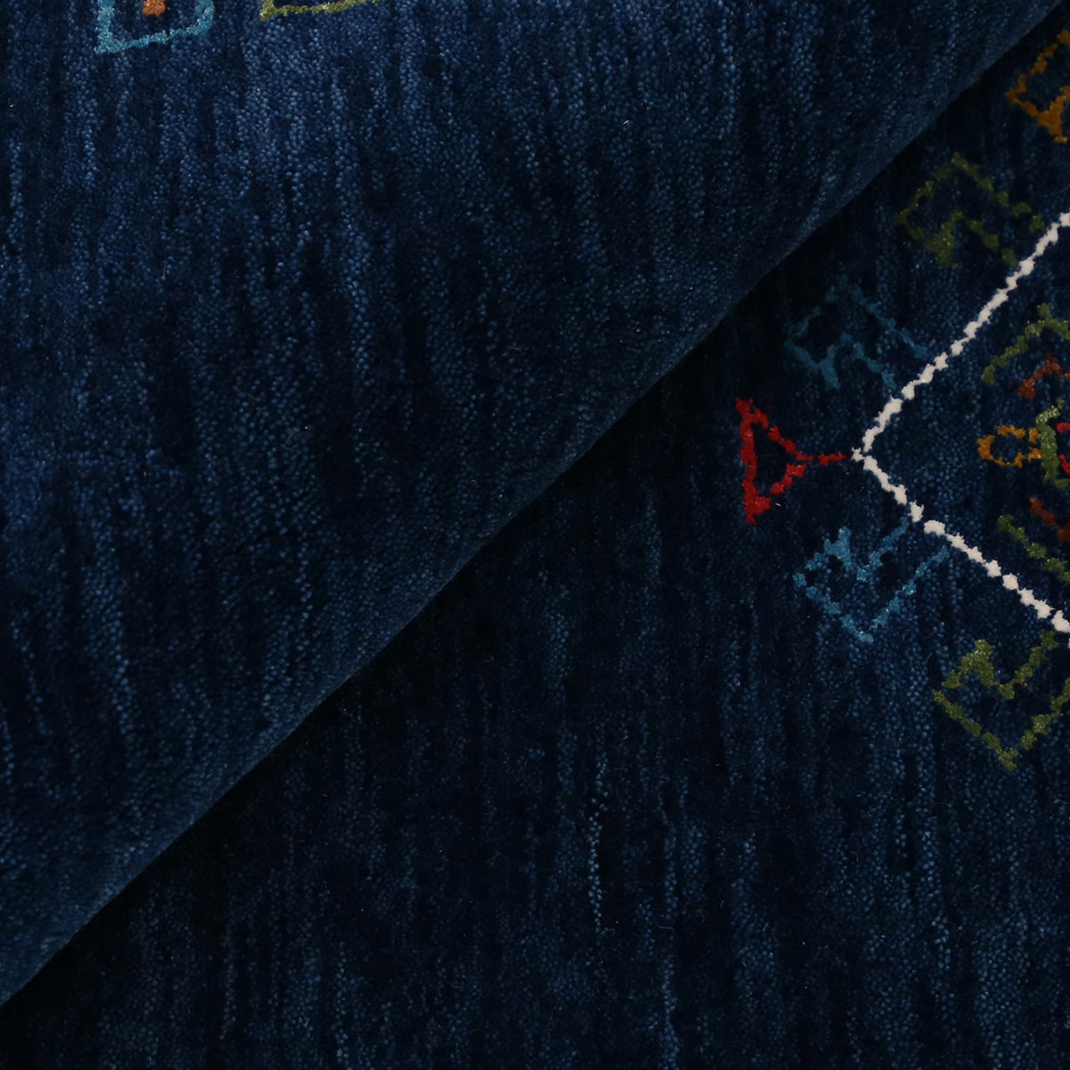Close-up of deep navy blue Hand Woven Loom Lori wool rug showing central diamond motif, colourful tribal details and natural wool texture