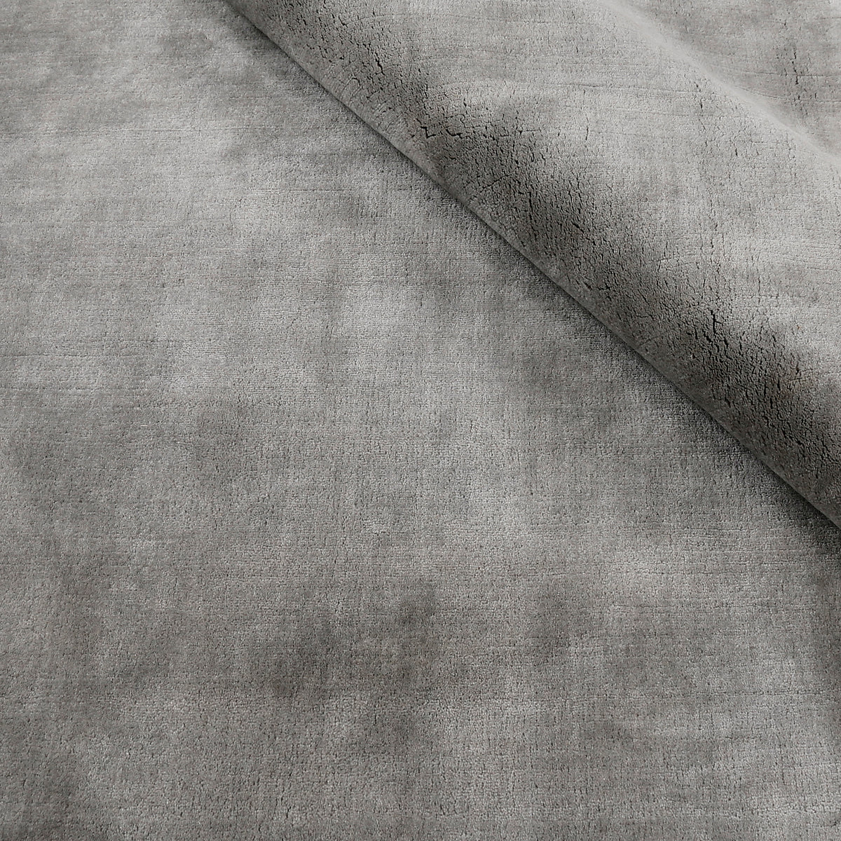 Close-up of grey Hand Woven Loom Lori wool rug with folded edge highlighting its soft 12–15 mm pile, smooth wool texture and subtle tonal surface variations.