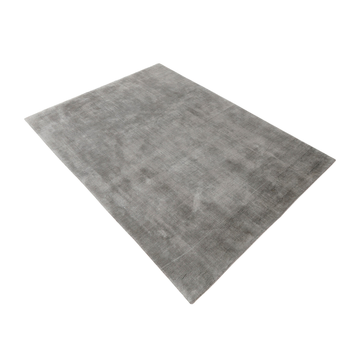 Side angle view of grey hand woven Loom Lori wool rug showing its rectangular shape, smooth plain surface and subtle tonal variations.