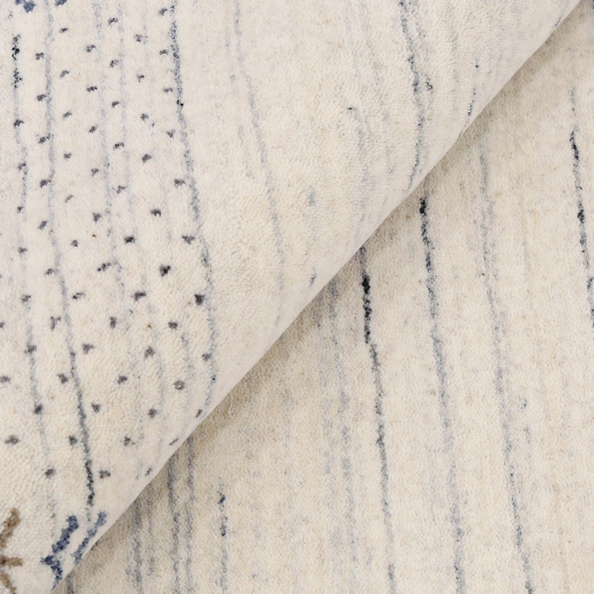 Close-up of ivory Hand Woven Loom Lori wool rug showing natural texture, blue-grey striations and symbolic folk motifs