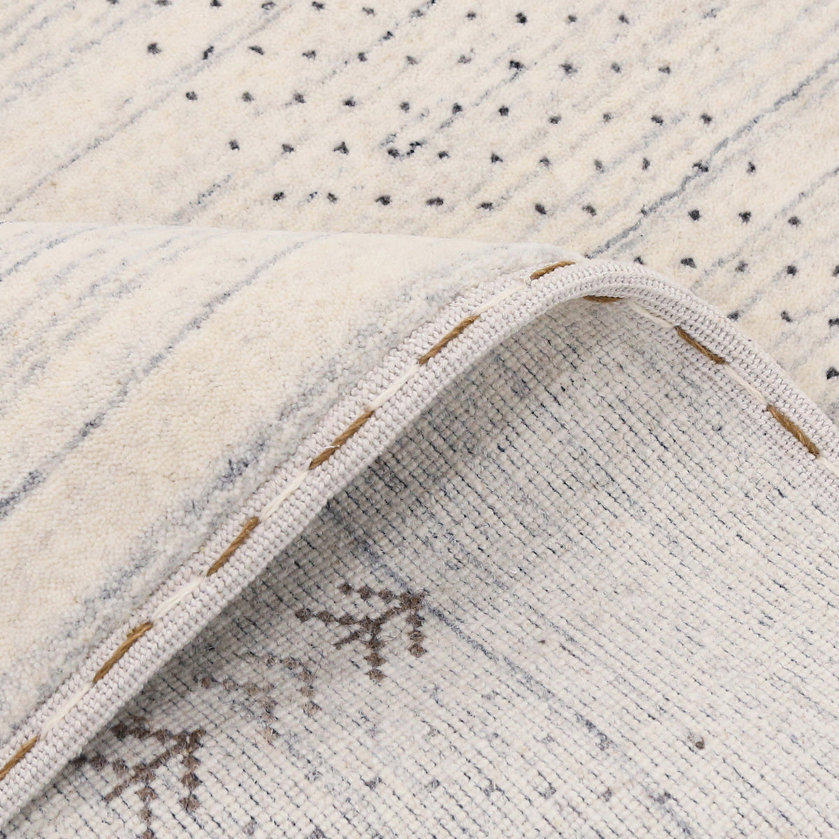 Close-up of ivory Hand Woven Loom Lori wool rug showing natural texture, blue-grey striations and symbolic folk motifs