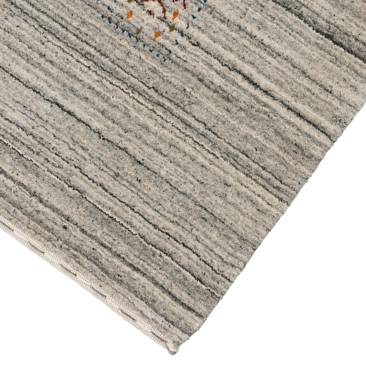 Corner and edge detail of ivory grey Hand Woven Loom Lori wool rug showing natural striations and handcrafted finishing