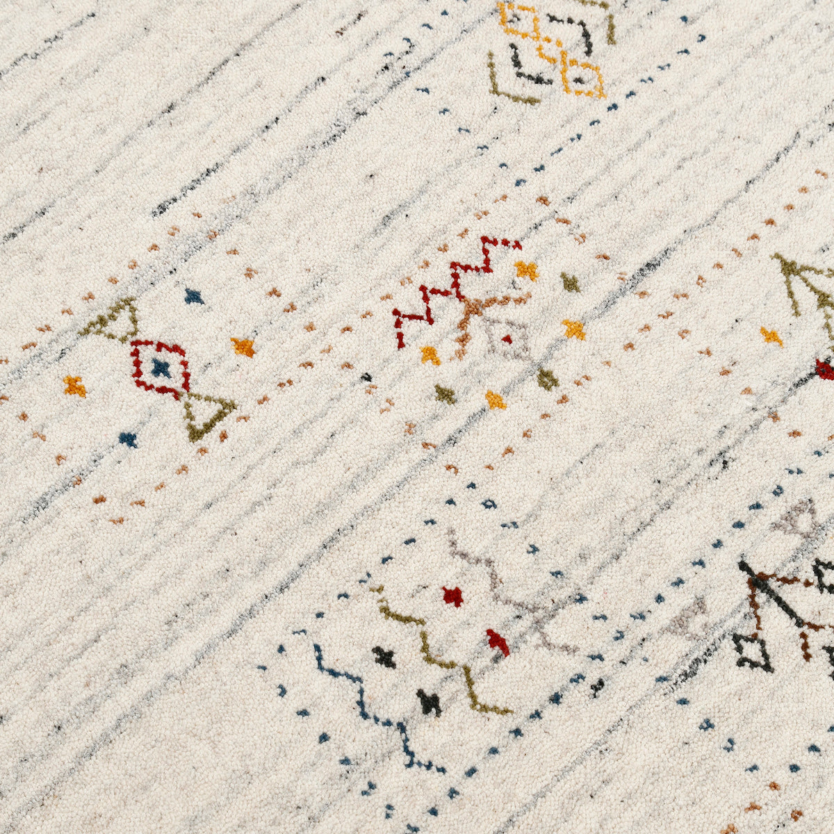Close-up of ivory cream Hand Woven Loom Lori wool rug showing grey-blue striations, dotted panels and colourful tribal motifs