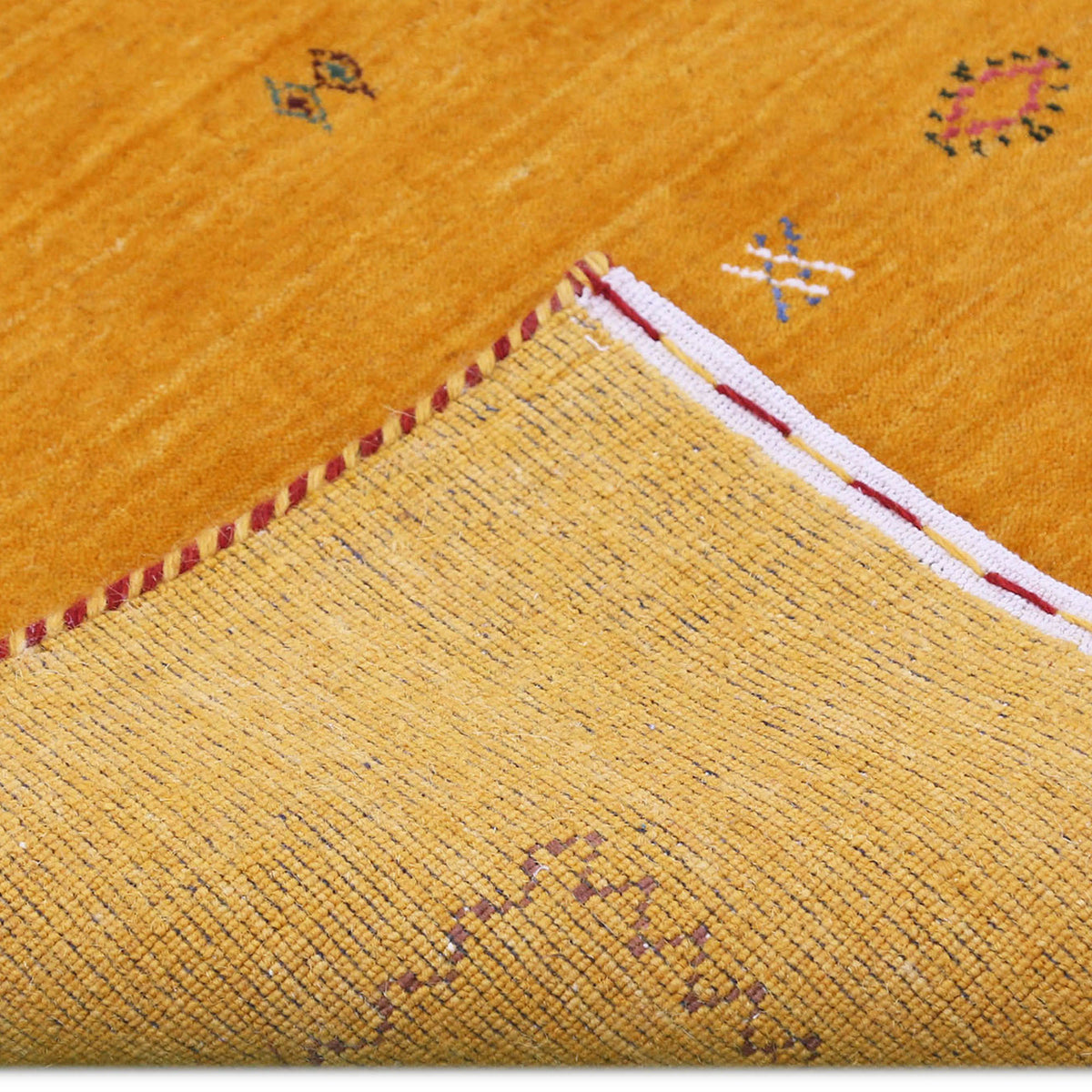 Corner and edge detail of golden mustard Loom Lori wool rug showing dark zigzag border and traditional handcrafted finishing