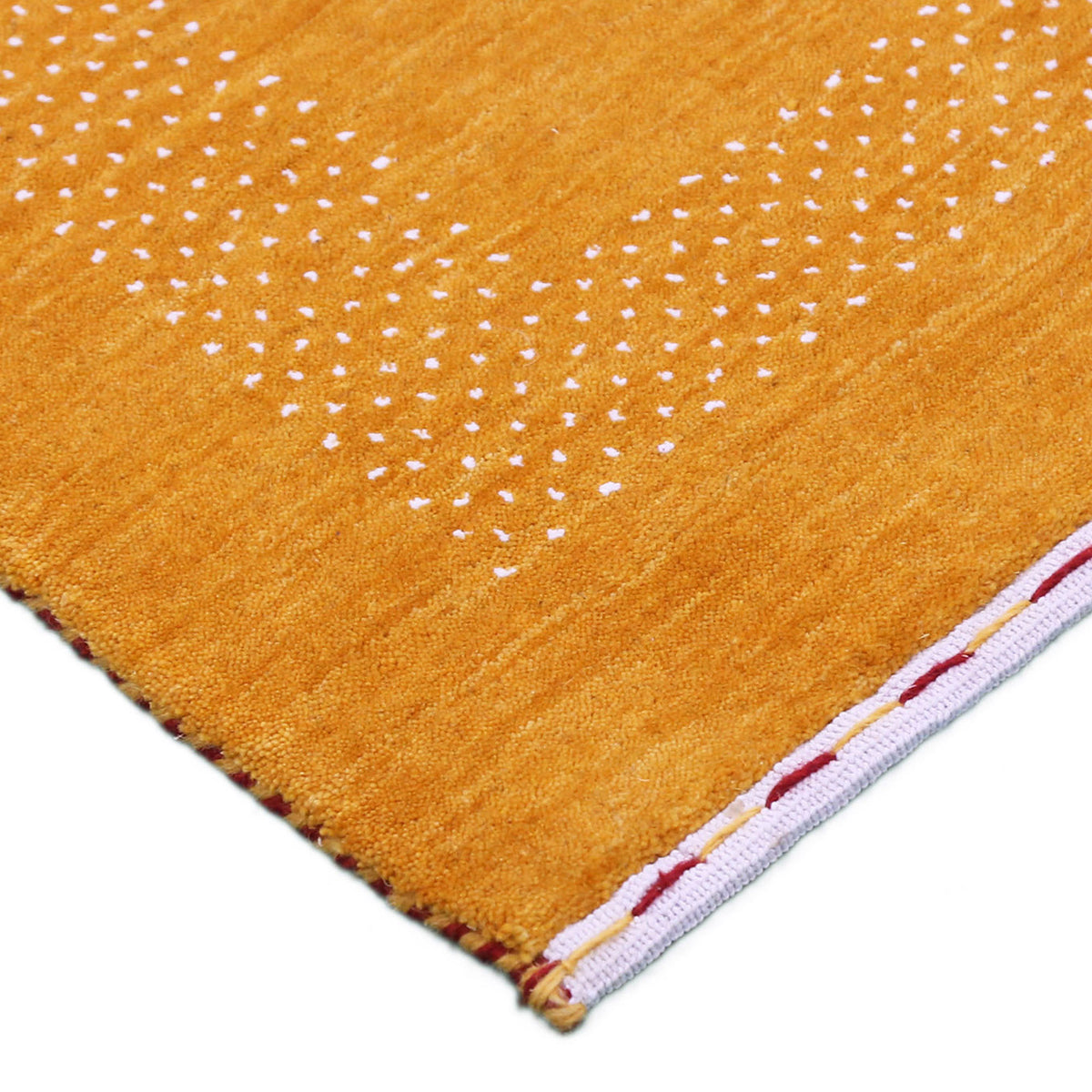 Corner and edge detail of mustard yellow Hand Woven Loom Lori wool rug showing dotted geometric border and handcrafted finishing