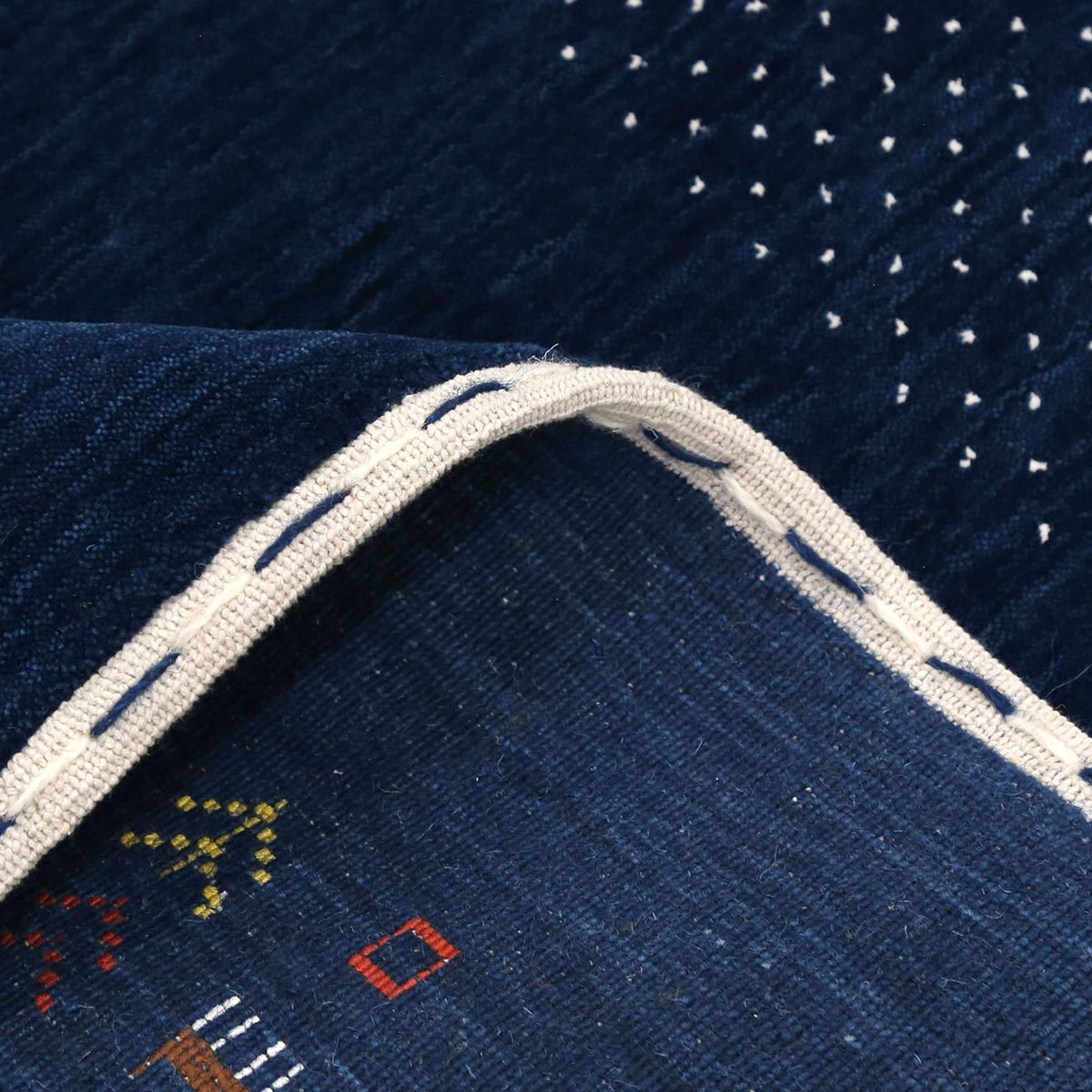 Close-up of navy blue Hand Woven Loom Lori wool rug showing natural wool texture, botanical symbols and colourful tribal motifs