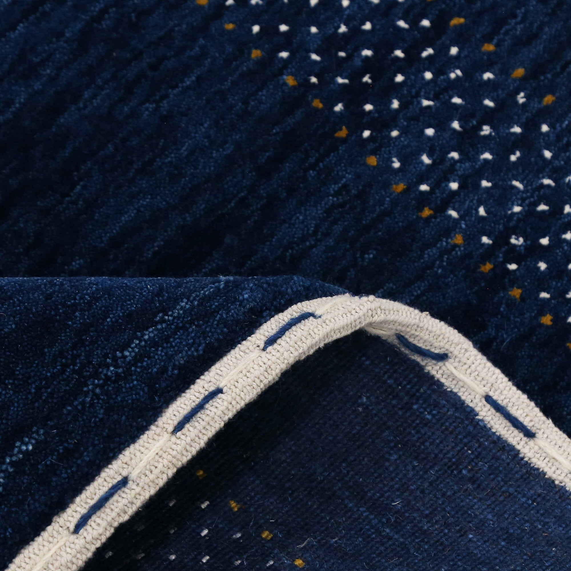 Corner and edge detail of navy blue Hand Woven Loom Lori wool rug showing dotted geometric border and handcrafted finishing