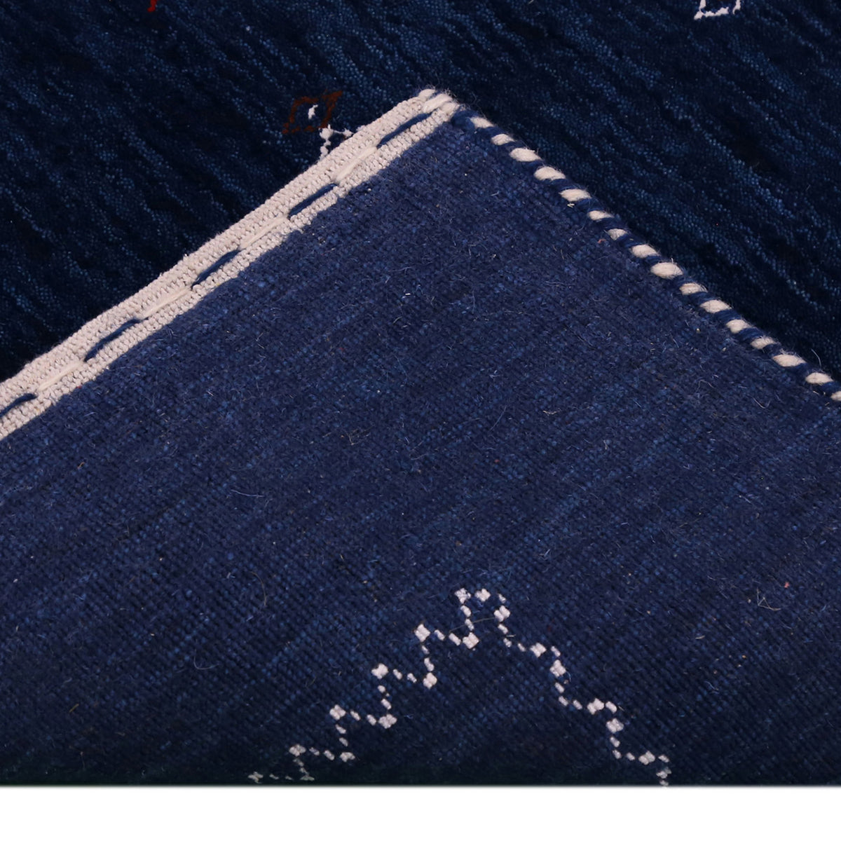 Corner and edge detail of navy blue Loom Lori wool rug showing contrasting ivory zigzag border and handcrafted finishing