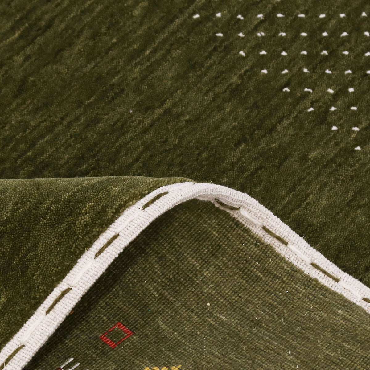 Close-up of olive green Hand Woven Loom Lori wool rug showing natural wool texture, botanical symbols and colourful tribal motifs