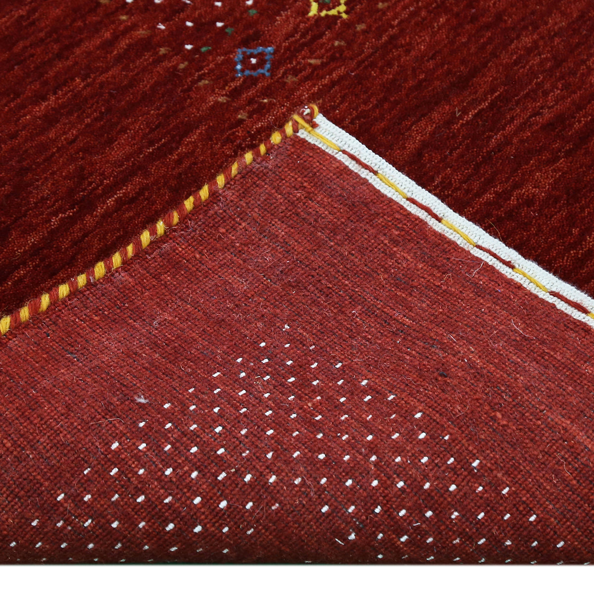 Corner and edge detail of red Hand Woven Loom Lori wool rug showing dotted border and handcrafted finishing