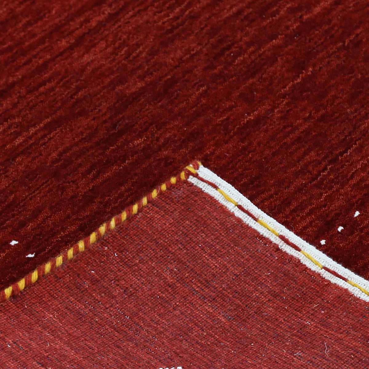 Corner and edge detail of red Hand Woven Loom Lori wool rug showing zigzag geometric border and handcrafted finishing