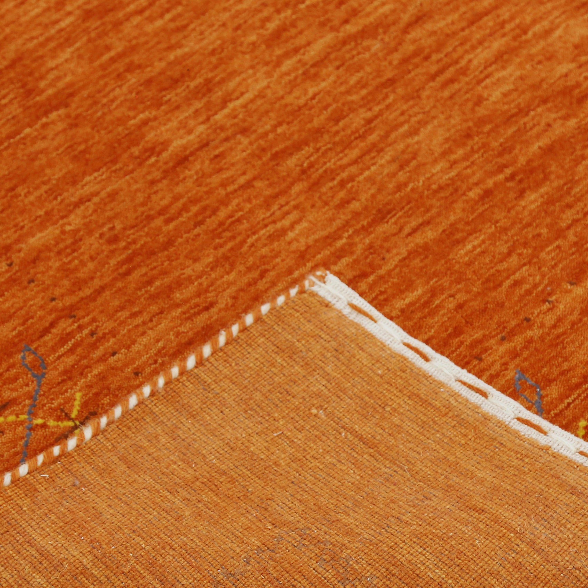 Corner and edge detail of rust orange Hand Woven Loom Lori wool rug showing geometric border and handcrafted finishing