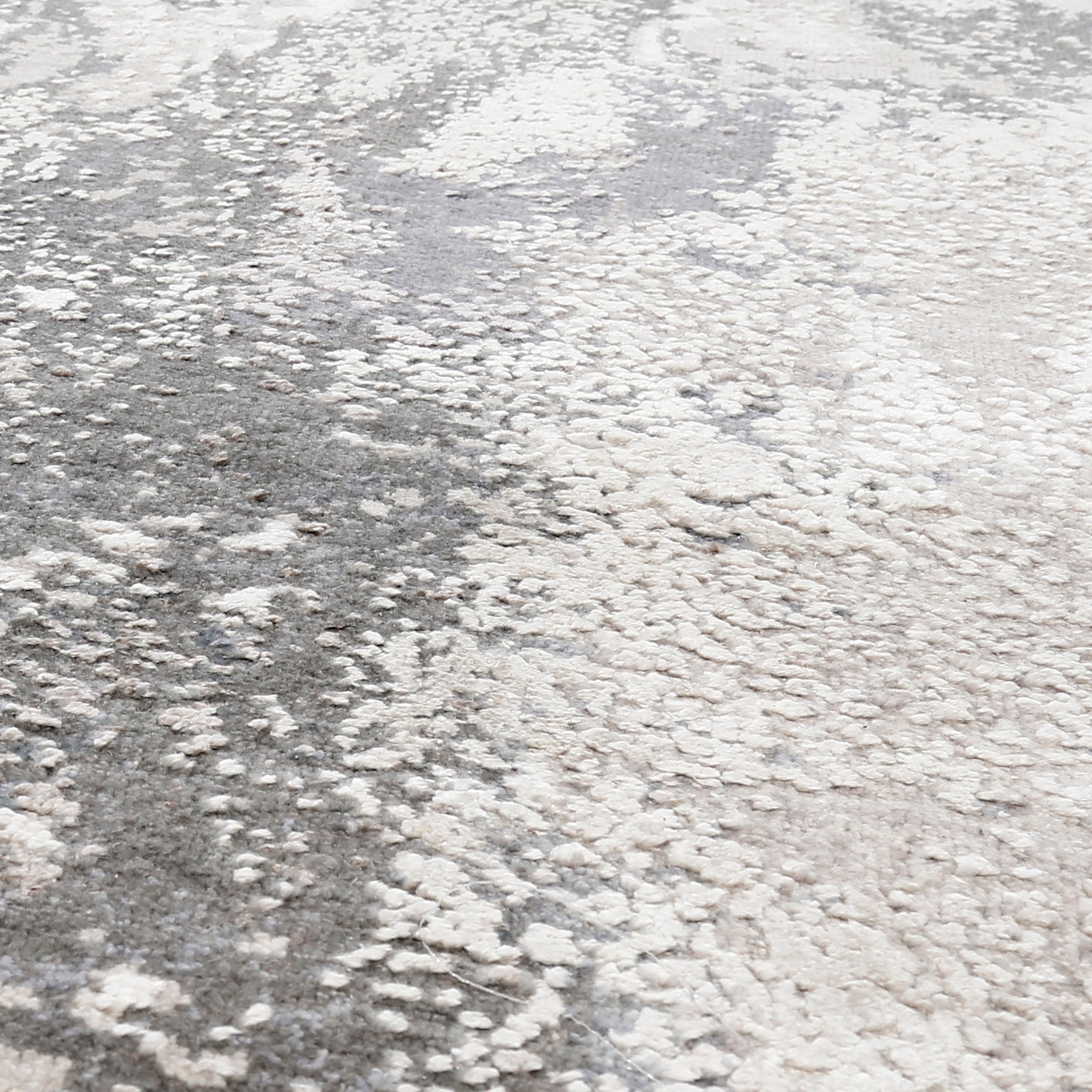 Close-up of the hand knotted wool and viscose texture with silver grey ivory beige and muted blue abstract detailing