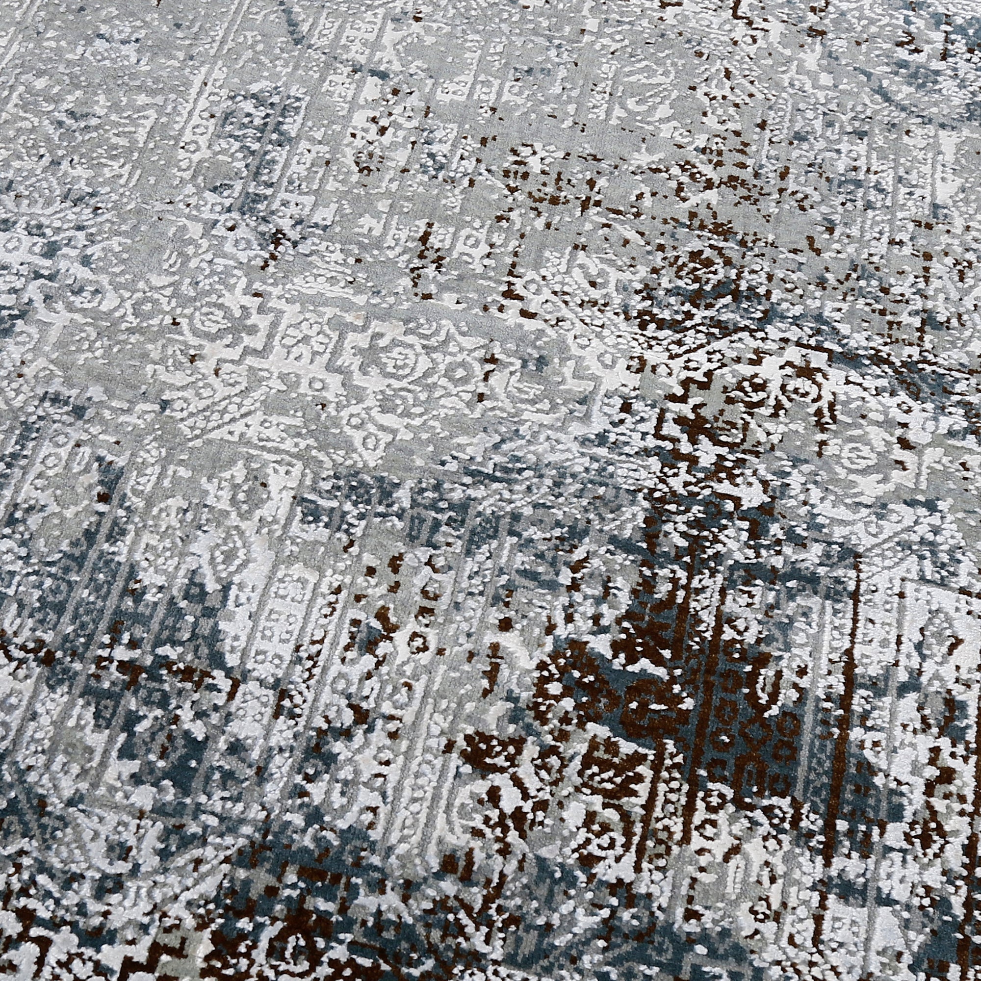 Close-up of the hand knotted wool and viscose texture with silver grey slate and distressed geometric detailing