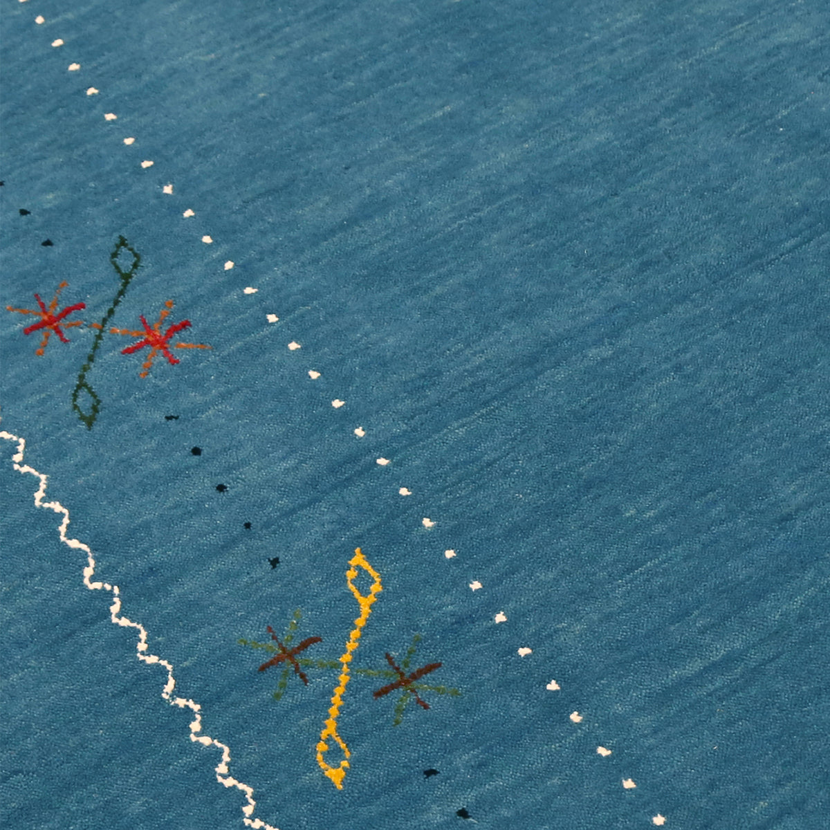 Close-up texture of teal blue Hand Woven Loom Lori wool rug showing natural wool fibres and delicate floral motif detailing