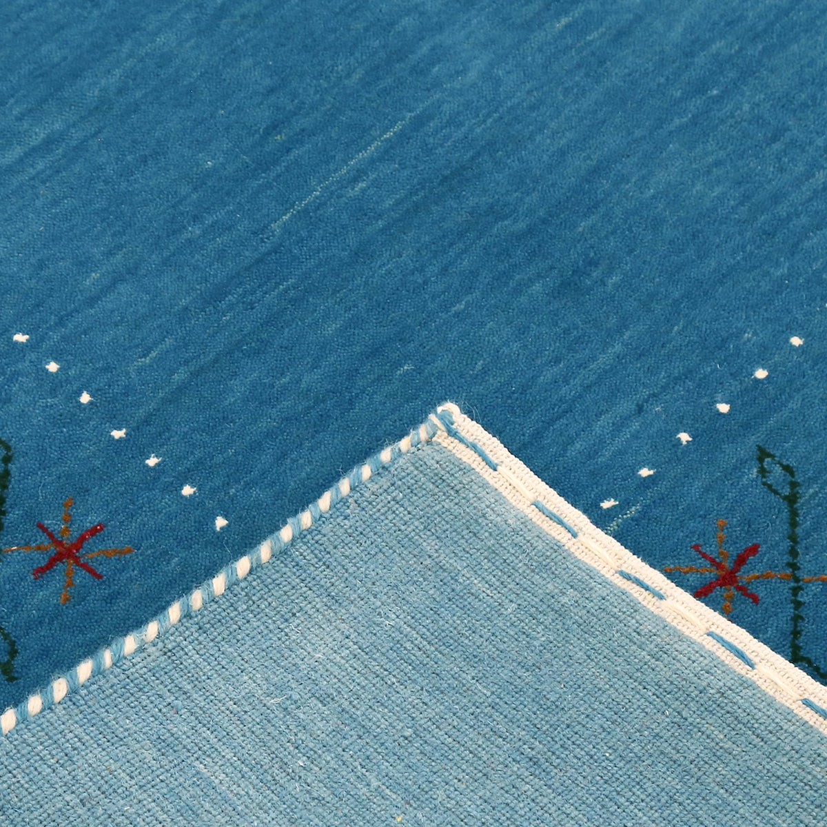 Corner and edge detail of teal blue Hand Woven Loom Lori wool rug showing zigzag border and handcrafted finishing