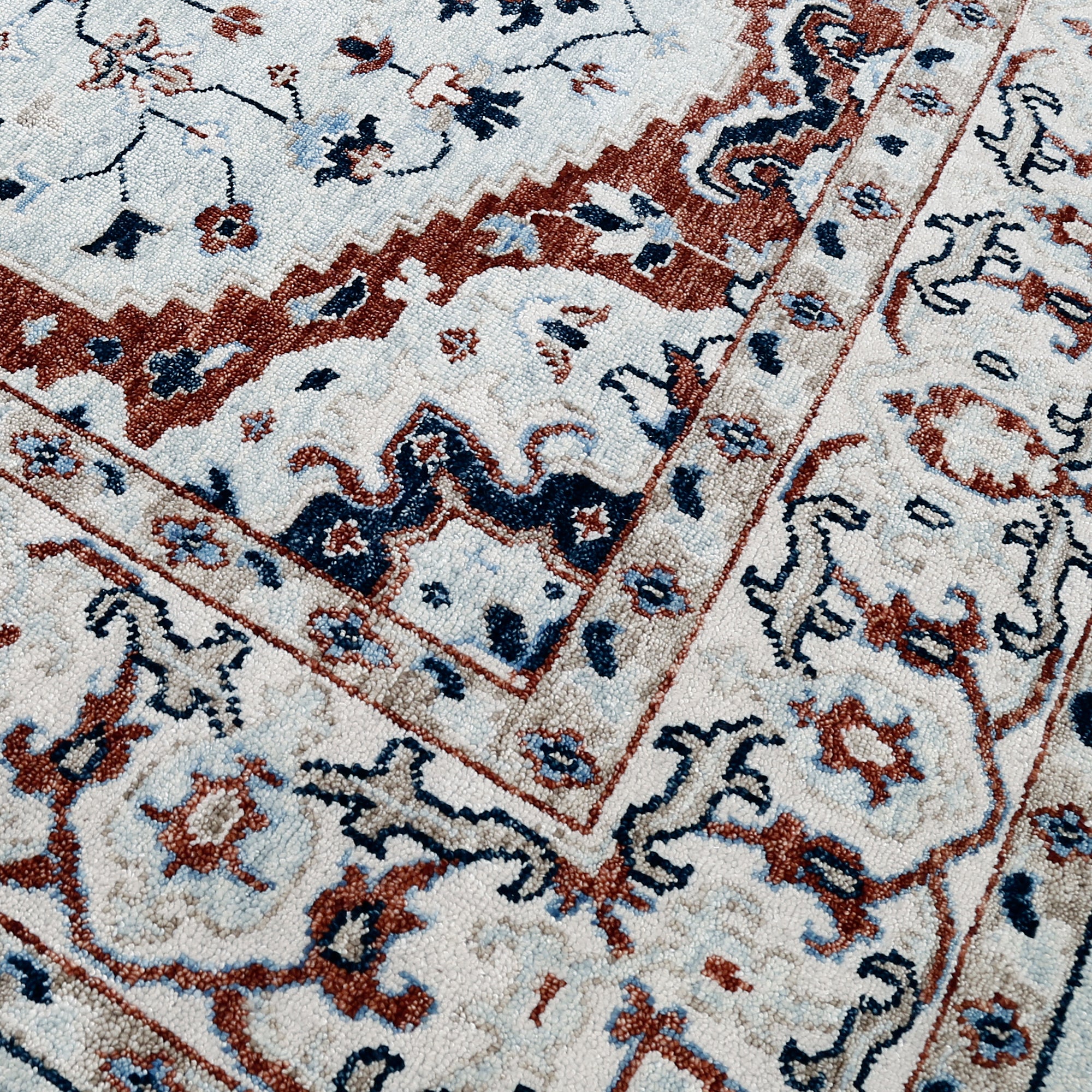 Detail view of hand knotted traditional wool rug in ivory navy and rust tones