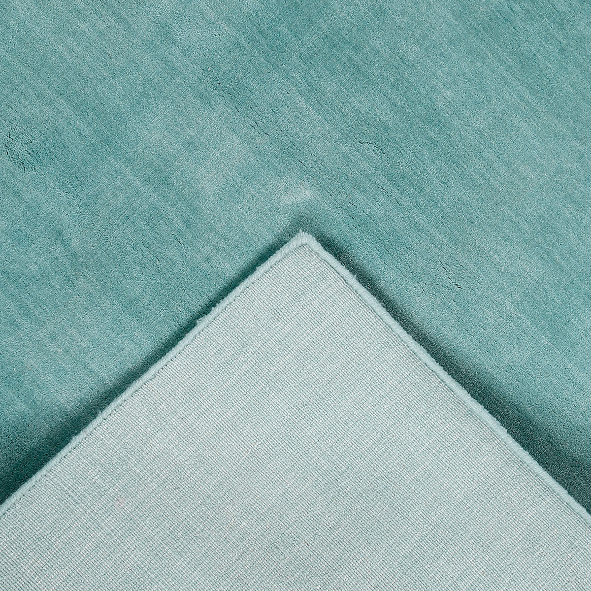 Back detail of a turquoise hand woven Loom Lori wool rug showing the woven underside, finished edge and handcrafted construction.