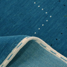 Close-up texture of teal blue Hand Woven Loom Lori wool rug showing natural wool fibres and delicate floral motif detailing