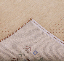 Corner and edge detail of natural beige Loom Lori wool rug showing dotted border, tribal motifs and handcrafted finishing