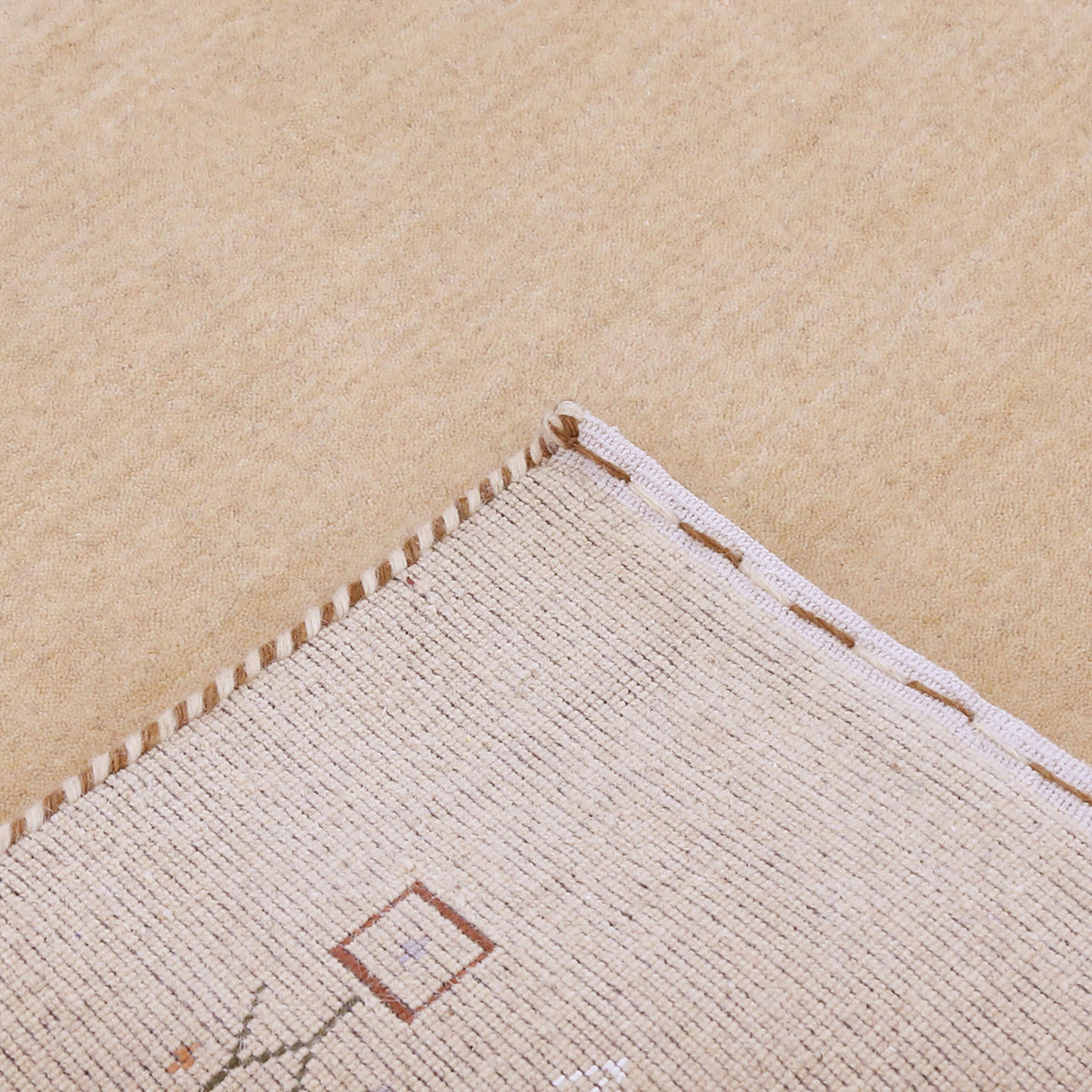 Corner and edge detail of natural beige Loom Lori wool rug showing geometric motifs and traditional handcrafted finishing