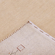 Corner and edge detail of natural beige Loom Lori wool rug showing geometric motifs and traditional handcrafted finishing