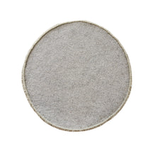 Side angle view of beige smiley face wool kids rug showing its plush hand tufted pile, round shape and playful cartoon design.