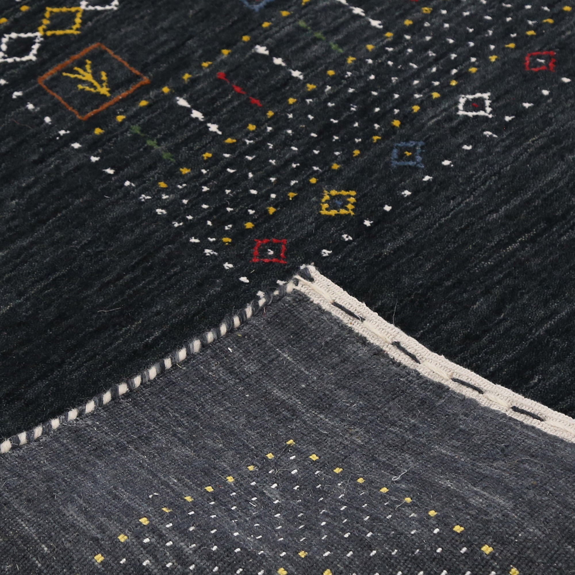 Corner and edge detail of black Hand Woven Loom Lori wool rug showing geometric border and handcrafted finishing