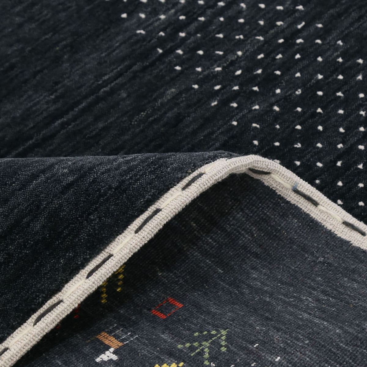 Close-up of charcoal black Hand Woven Loom Lori wool rug showing natural wool texture, botanical symbols and earthy tribal motifs