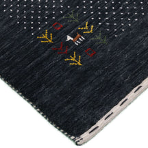 Corner and edge detail of charcoal black Loom Lori wool rug showing ivory dotted sections, folk motifs and handcrafted finishing