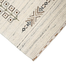 Corner and edge detail of ivory cream Hand Woven Loom Lori wool rug showing grey striations and handcrafted finishing