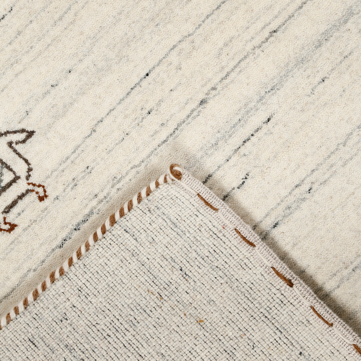 Corner and edge detail of ivory cream Hand Woven Loom Lori wool rug showing grey striations and handcrafted finishing