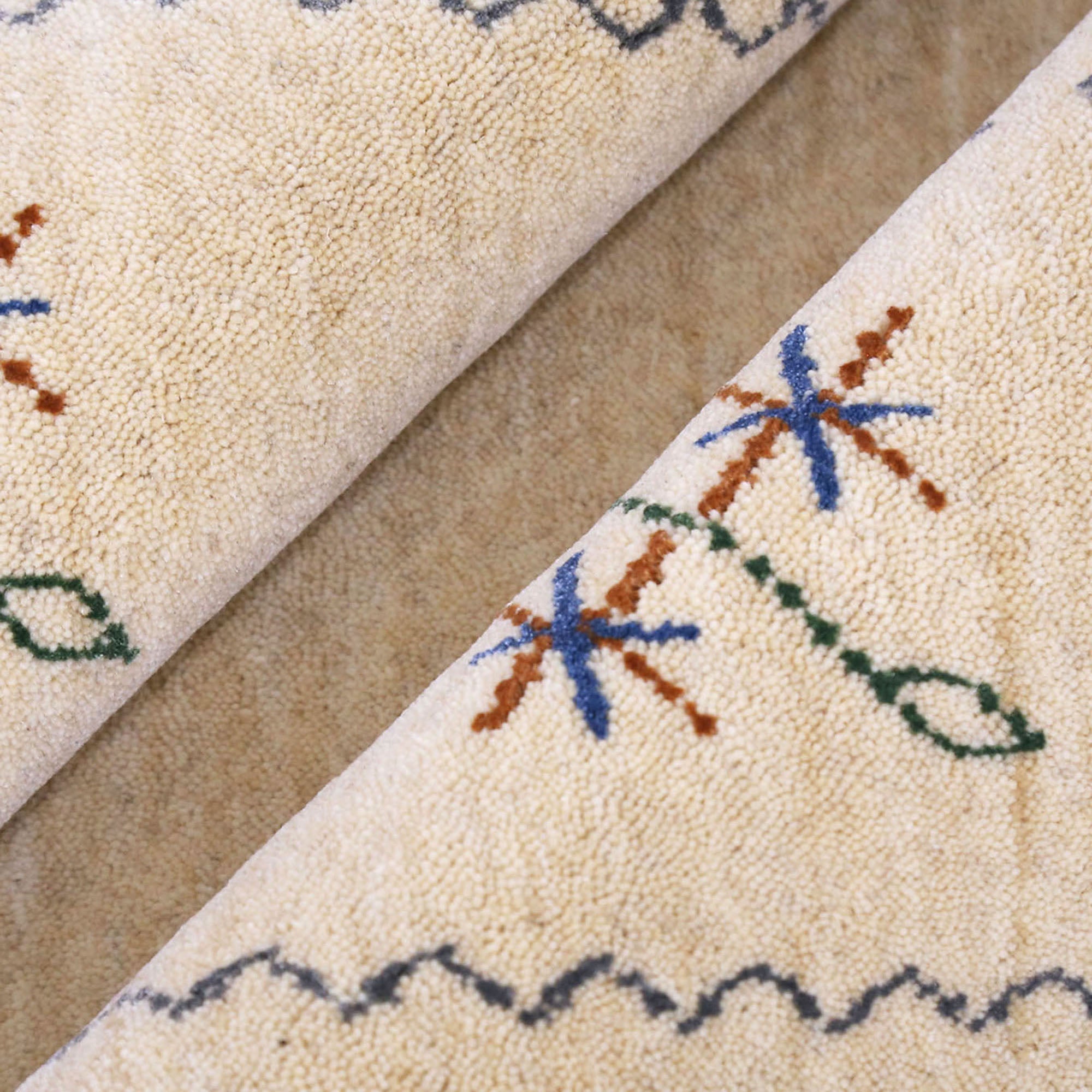 Close-up texture of cream Hand Woven Loom Lori wool rug showing natural wool fibres and delicate floral motif detailing