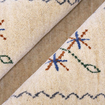 Close-up texture of cream Hand Woven Loom Lori wool rug showing natural wool fibres and delicate floral motif detailing