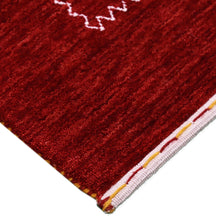 Corner and edge detail of crimson red Loom Lori wool rug showing contrasting ivory zigzag border and handcrafted finishing