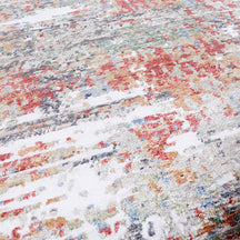 Close-up of Crimson Mist hand knotted viscose rug with ivory grey red rust and blue distressed detailing