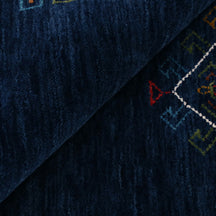 Close-up of deep navy blue Hand Woven Loom Lori wool rug showing central diamond motif, colourful tribal details and natural wool texture