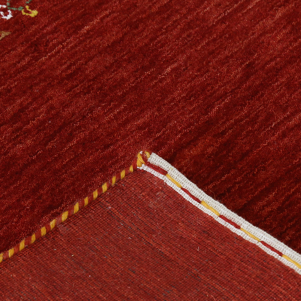 Corner and edge detail of deep red Hand Woven Loom Lori wool rug showing handcrafted finish and tribal pattern details
