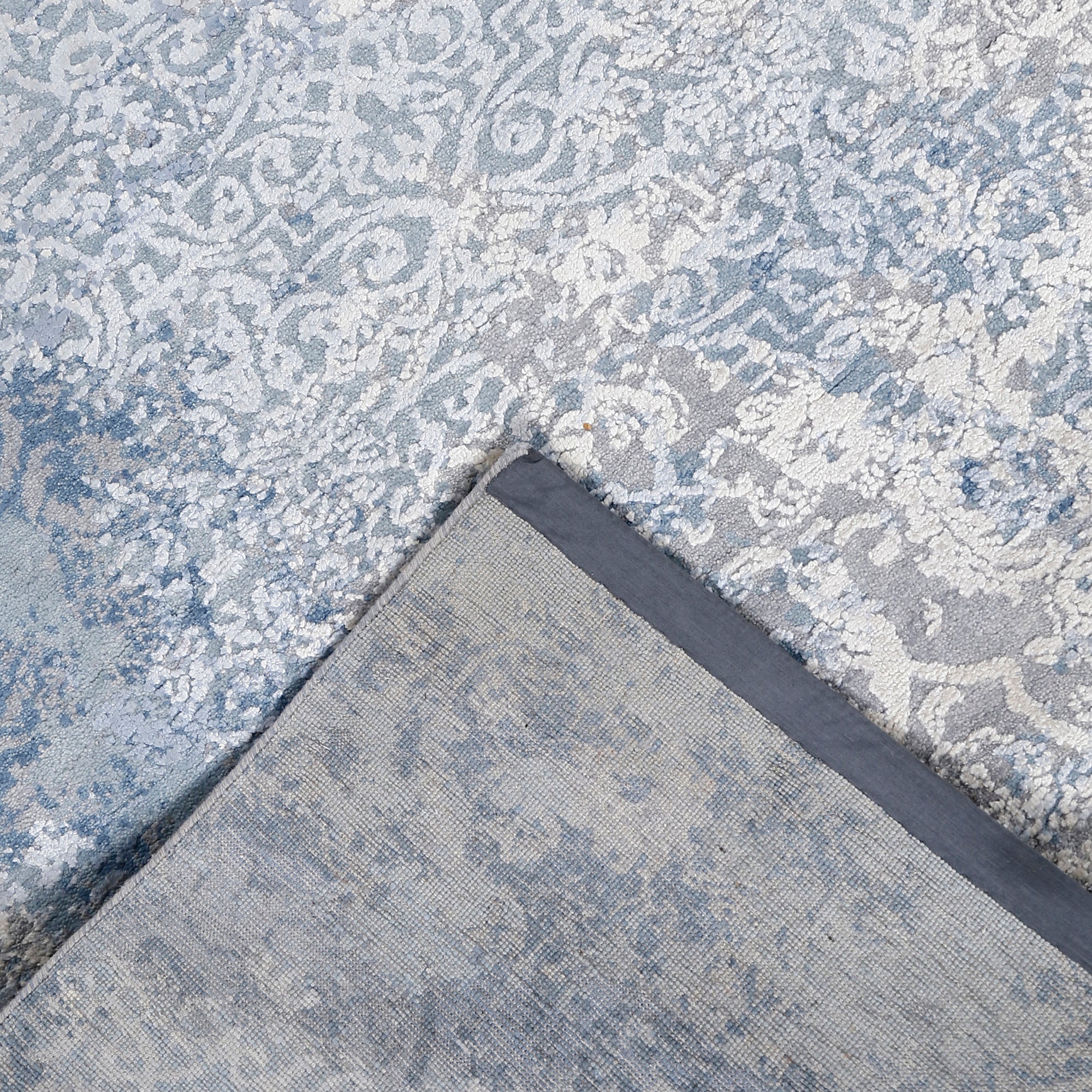 Hand-finished edge and faded ornamental detailing of the frost blue hand knotted rug