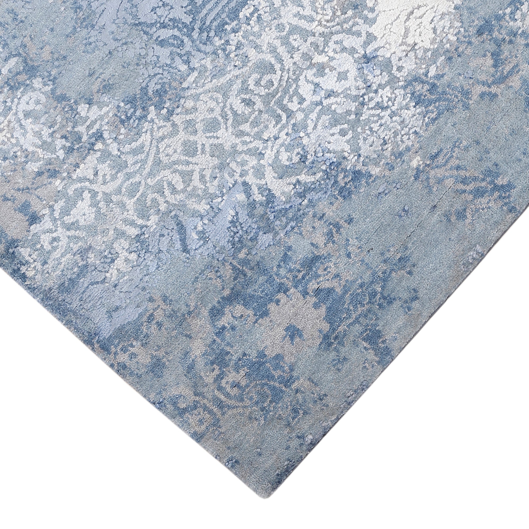 Hand-finished edge and faded ornamental detailing of the frost blue hand knotted rug