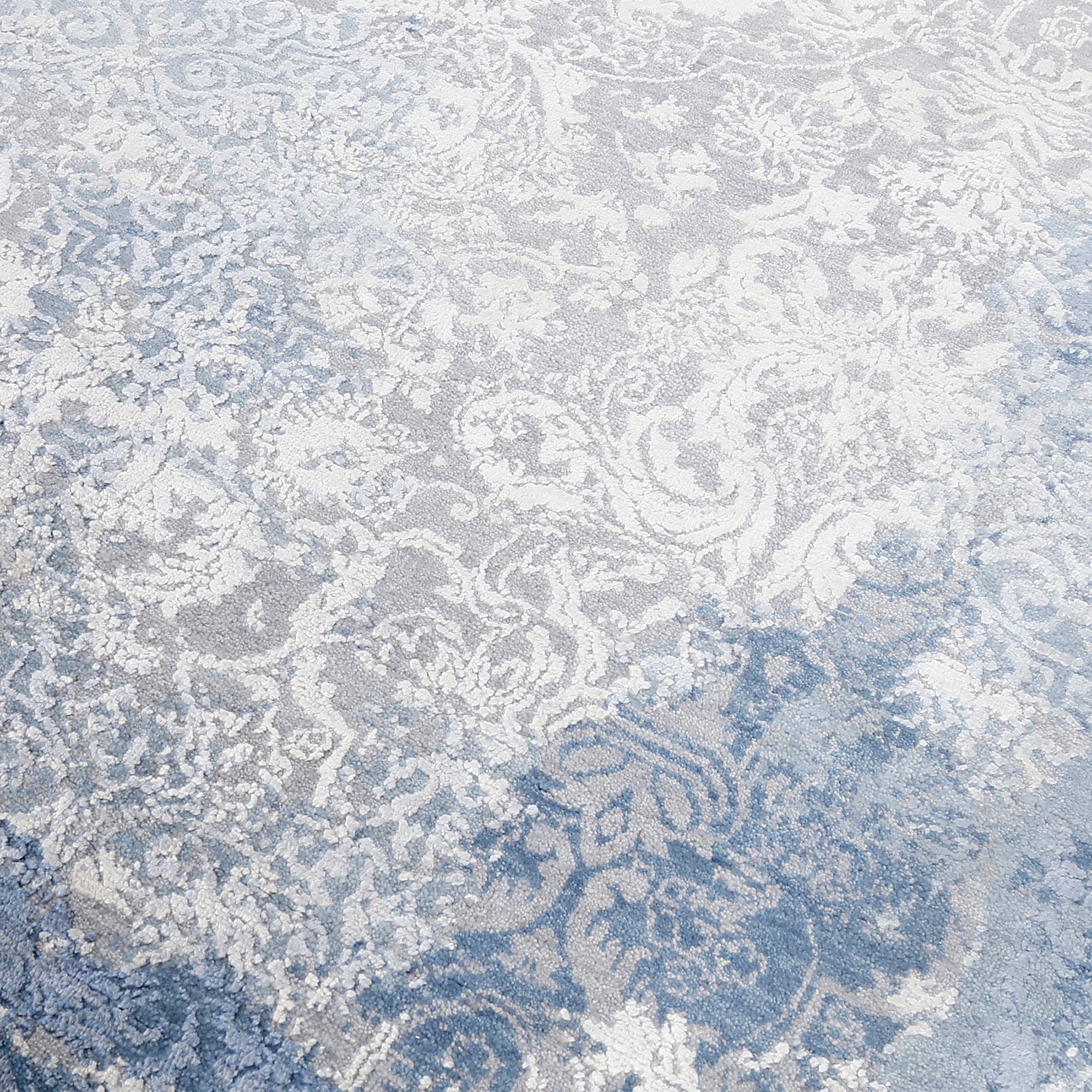 Close-up of the hand knotted wool and viscose texture with frost-blue distressed damask detailing