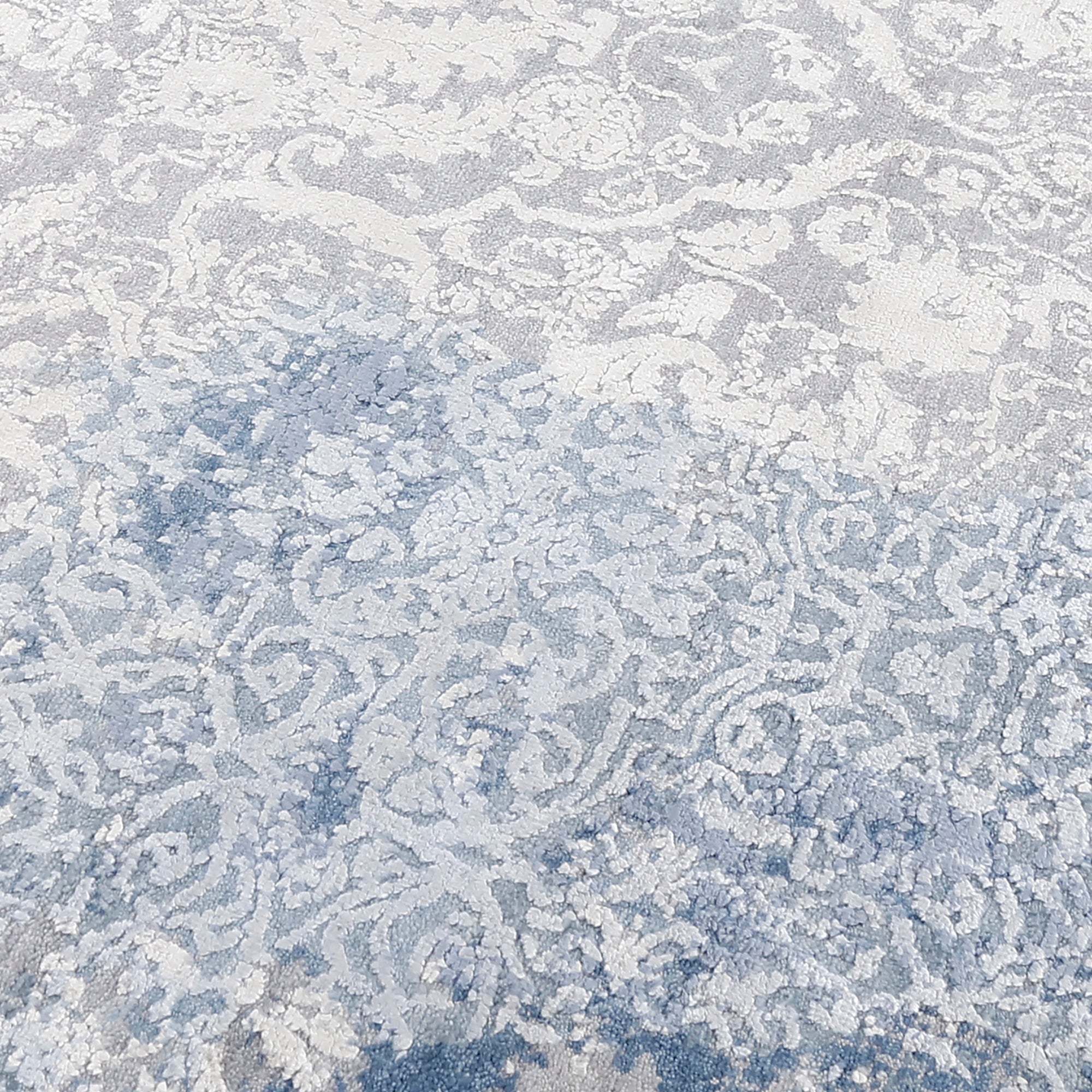 Close-up of the hand knotted wool and viscose texture with frost-blue distressed damask detailing